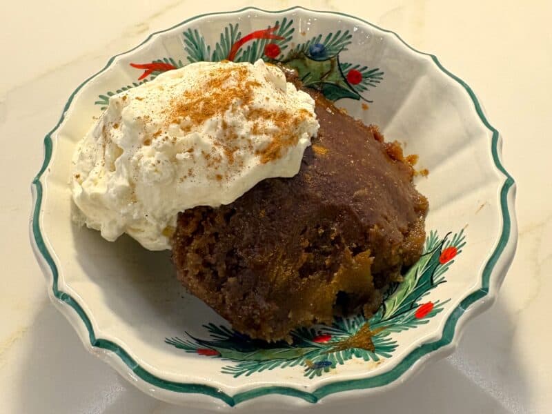 figgy pudding in a holiday dish with whipped cream on top